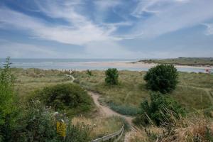 a dirt path leading to a beach with the ocean at Pilots Rest in Alnmouth