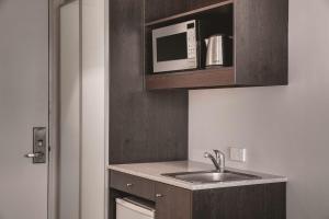 a small kitchen with a sink and a microwave at Travelodge Hotel Hobart in Hobart