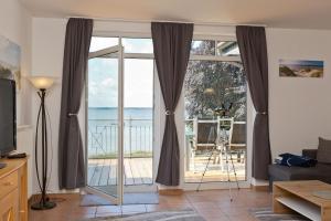 - un salon avec une porte coulissante en verre offrant une vue sur l'océan dans l'établissement Haus am Kölpinsee App 3 3, à Kölpinsee