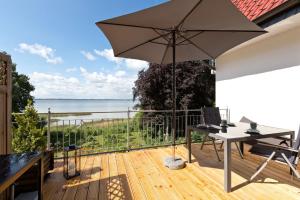 une terrasse avec une table et un parasol dans l'établissement Haus am Kölpinsee App 3 3, à Kölpinsee