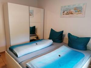 2 camas en una habitación con almohadas azules en Haus am Kölpinsee App 1 4 en Kölpinsee