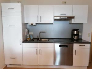 una cocina con armarios blancos y fregadero en Haus am Kölpinsee App 1 4 en Kölpinsee