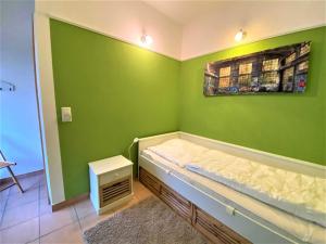 a bedroom with a green wall with a bed in it at Haus am Kölpinsee App 4 4 in Kölpinsee