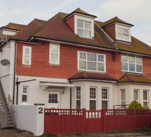 a red and white house with a red fence at Beachy Head Apartment By Air Premier in Seaford
