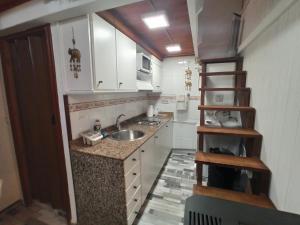 a small kitchen with white cabinets and a sink at La Casita in Gijón