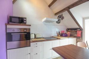 a kitchen with a stove and a microwave at Rafters in Alnmouth
