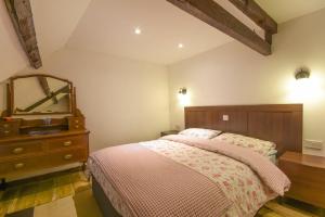 1 dormitorio con cama, tocador y espejo en Rafters, en Alnmouth