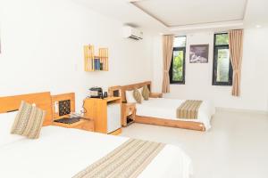 Trung Nguyên Coffee Resort في بون ما توت: سريرين في غرفة بجدران بيضاء ونوافذ