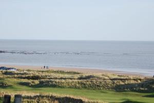 a group of people standing on a beach near the ocean at Rafters in Alnmouth