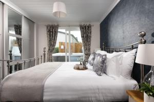 a bedroom with a large bed with white pillows at Hazel Lodge, 27 Roadford Lake Lodges in Lifton