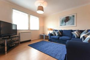 a living room with a blue couch and a tv at Beachcomber Apartment in Bamburgh