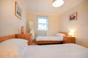een slaapkamer met 2 bedden en een raam bij Beachcomber Apartment in Bamburgh