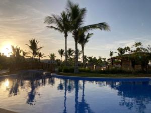 a swimming pool with palm trees and the sunset at Townhouse Paolo in Salalah