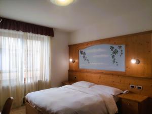 um quarto com uma cama branca e uma janela em Hotel Ariston ***S em Madonna di Campiglio