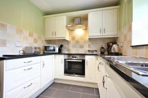 a kitchen with white cabinets and a stove top oven at Greenfinch in Lucker