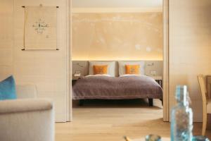ein Schlafzimmer mit einem Bett mit orangefarbenen Kissen in der Unterkunft Strandhotel am Weissensee in Weissensee