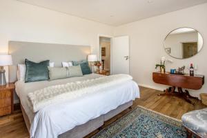 a bedroom with a large white bed and a mirror at Far Horizons Camps Bay in Cape Town