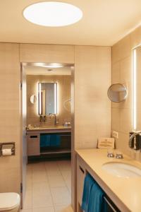 ein Badezimmer mit einem Waschbecken, einem WC und einem Spiegel in der Unterkunft Strandhotel am Weissensee in Weissensee