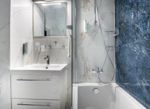een witte badkamer met een wastafel en een douche bij Apartamenty Yeti & Wilka w Centrum Chorzowa - Yeti in Chorzów
