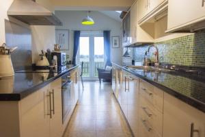 a large kitchen with white cabinets and a large window at Our Story Cottage in Long Houghton