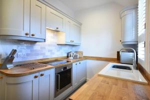 a kitchen with white cabinets and a sink at Periwinkle in Bamburgh