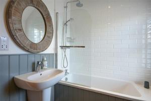 a bathroom with a sink and a mirror and a tub at Periwinkle in Bamburgh +15 photos