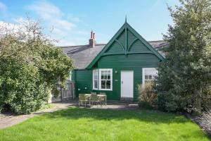a green house with a table and chairs in the yard at Periwinkle in Bamburgh