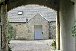 une grange avec une porte dans un bâtiment en pierre dans l'établissement Swallow Cottage nr Powburn, à Ingram