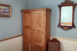 einen Holzschrank in einem Zimmer mit Spiegel in der Unterkunft Swallow Cottage nr Powburn in Ingram