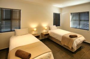 two beds in a room with two lamps and windows at Dalton's Langebaan in Langebaan