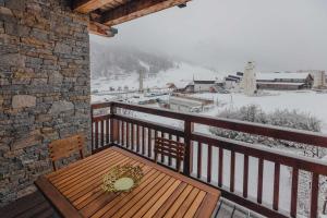 a wooden table on a balcony with a snow covered mountain at Apt 102, Les Chalets du Chaberton, pied de pistes et Spa in Montgenèvre