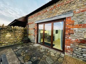 a brick building with a large window and a patio at Stable Cottage in Frome