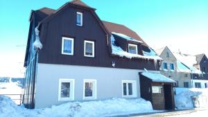 ein weißes Haus mit schwarzem Dach im Schnee in der Unterkunft Chalupa Hela in Loučná pod Klínovcem