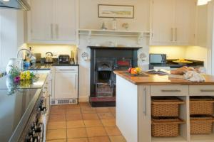 a kitchen with white cabinets and a stove top oven at The Villas No3 in Embleton +5 photos