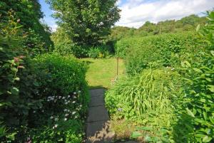un jardín con arbustos y una pasarela en Riverside Cottage en Warkworth