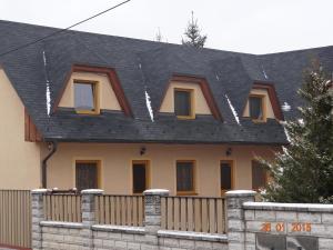 a house with a black roof and a fence at Penzion Eso in Martin