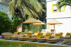 a group of chairs and umbrellas next to a pool at Bloom Hotel - Calangute in Calangute