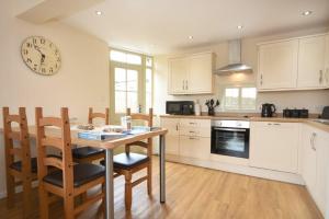 a kitchen with a table and a clock on the wall at Castle View Glororum in Bamburgh