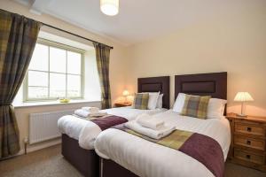 a bedroom with two beds and a window at Castle View Glororum in Bamburgh
