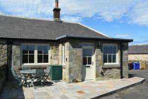 a stone cottage with a table and chairs outside at Castle View Glororum in Bamburgh