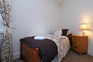 a bedroom with a bed and a night stand with a lamp at Sea Air in Amble