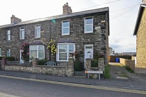 a brick house with a sign in front of it at Cladach Cottage in Seahouses