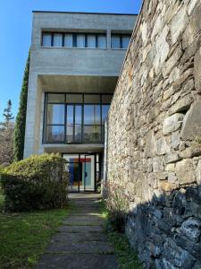 ein Gebäude mit einer Steinmauer neben einem Bürgersteig in der Unterkunft Villa Cavalli - Snozzi's Kunstwerk in Verscio