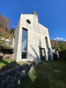 ein weißes Gebäude mit einem Fenster an einer Steinmauer in der Unterkunft Villa Cavalli - Snozzi's Kunstwerk in Verscio