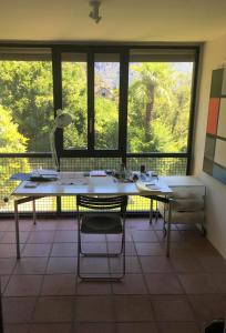 een grote kamer met een tafel, stoelen en ramen bij Villa Cavalli - Snozzi's Kunstwerk in Verscio