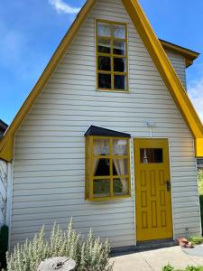 una casa blanca con puerta amarilla en Hostal Los Pioneros, en Puerto Natales