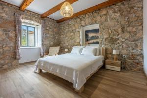 a bedroom with a bed and a stone wall at Villa Eirene in Drivenik +69 photos