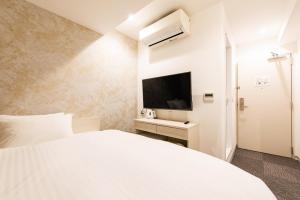 a bedroom with a white bed and a tv at Hotel The One Shinimamiya in Osaka