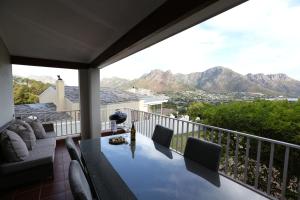a balcony with a table and chairs and mountains at Above & Beyond Houtbay in Hout Bay
