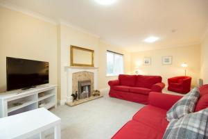 a living room with a red couch and a fireplace at Summerfold in Warkworth